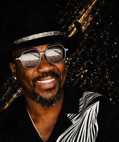 Anthony Hamilton smiling in a black and white patterned shirt